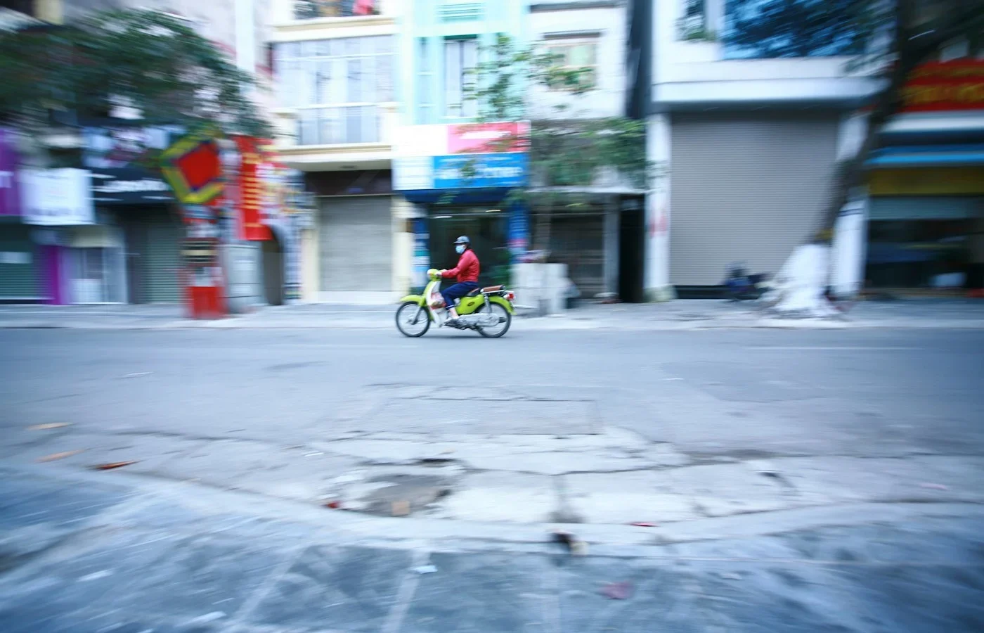 Ciclista con chaqueta roja por una calle de Vietnam, foto ilustrativa de alternativas de movilidad para viajeros en Hanói
