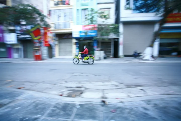Ciclista con chaqueta roja por una calle de Vietnam, foto ilustrativa de alternativas de movilidad para viajeros en Hanói