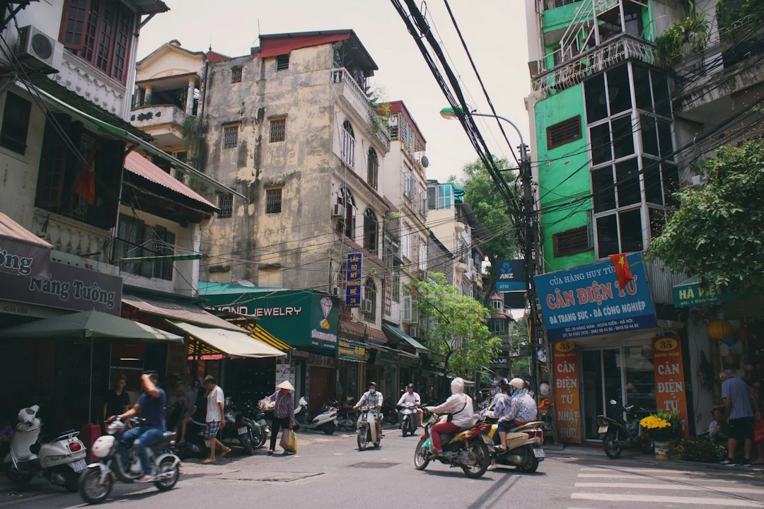 Straßenszene in Vietnam mit Menschen und Häusern als Symbolbild für den Vergleich von Rollern und anderen Verkehrsmitteln