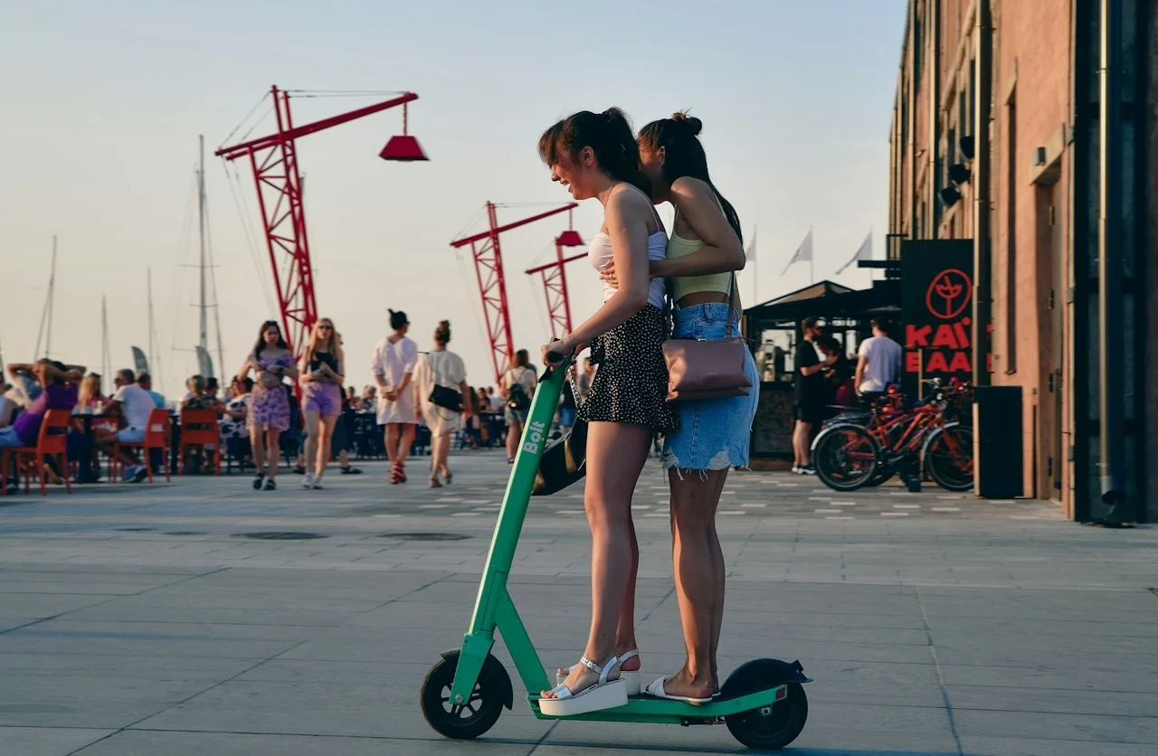 Zwei Frauen auf einem grünen elektrischen Roller in Tallinn, Symbolfoto für sichere Elektromotorradmiete in Hanoi