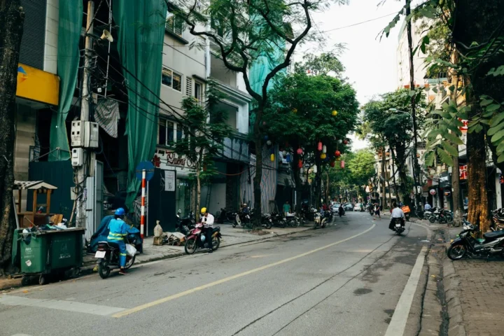 Personas en motocicletas en una calle urbana, ilustración de movilidad estudiantil y seguridad vial en Hanói