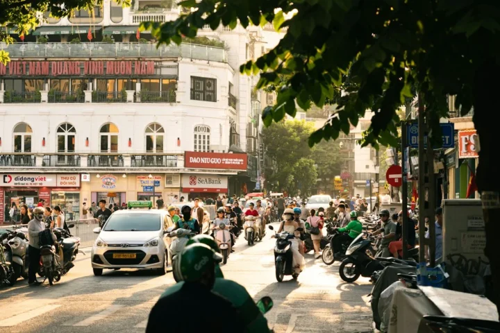 Tráfico de motocicletas y coche en una calle de Hanói al atardecer, ilustración de movilidad urbana