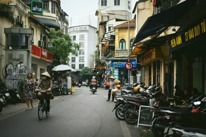 Phố Hà Nội với xe máy đỗ bên đường và người đi xe đạp, minh họa nhu cầu đi học và thuê xe máy của sinh viên