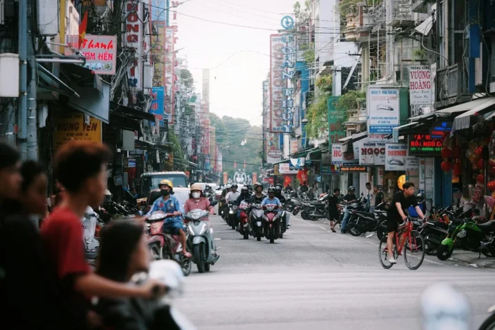 Calle concurrida de Hanói con motocicletas y edificios, imagen ilustrativa de alternativas de transporte